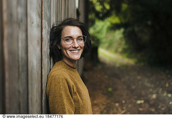 Happy woman leaning on wooden wall