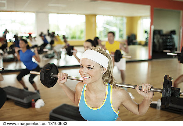 Happy woman lifting barbell in gym