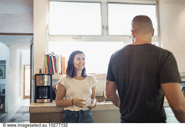 Happy woman looking at man in kitchen