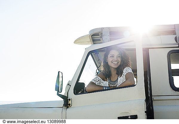 Happy woman looking through car window during sunny day