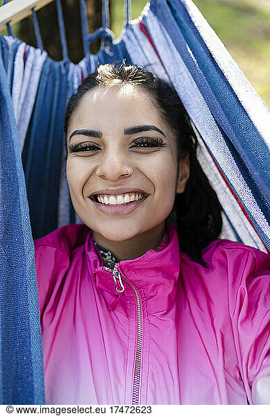 Happy woman lying in hammock at park