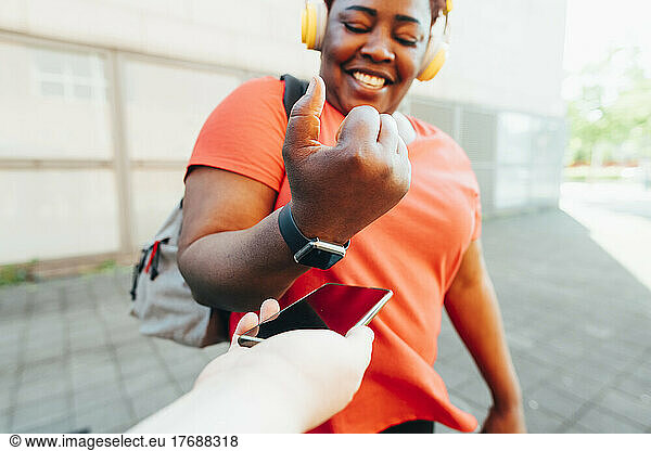 Happy woman making payment through smart watch