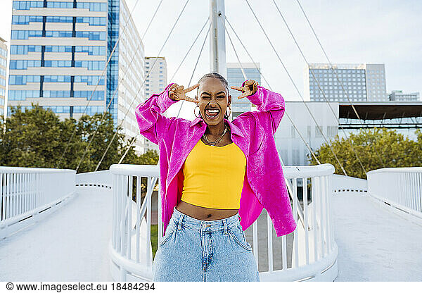 Happy woman peace sign gesture dancing on footbridge