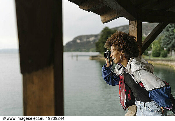 Happy woman photographing through camera under gazebo