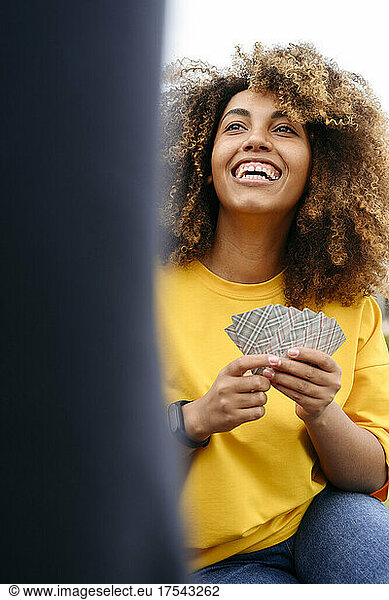 Happy woman playing cards outdoors