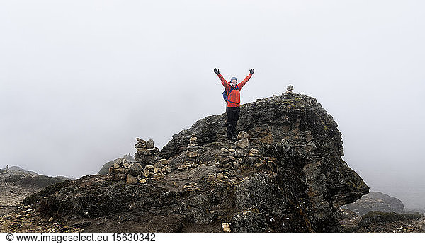 Happy woman raising arms  standing on rock  Himalayas  Solo Khumbu  Nepal