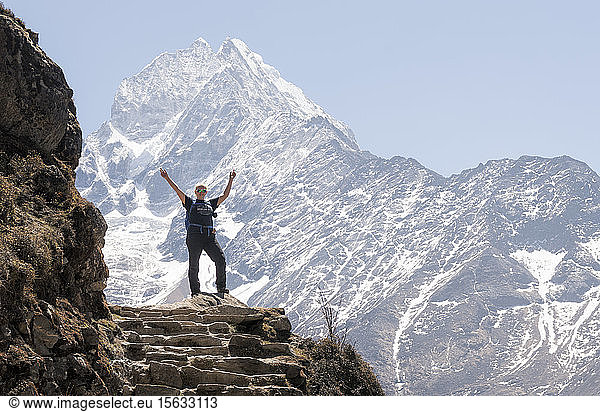 Happy woman raisng arms in front of Thamersku mountain  Himalayas  Solo Khumbu  Nepal