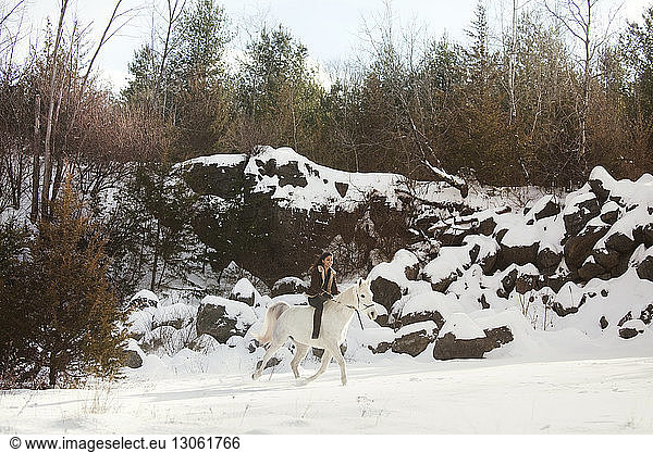 Happy woman riding horse on snow field