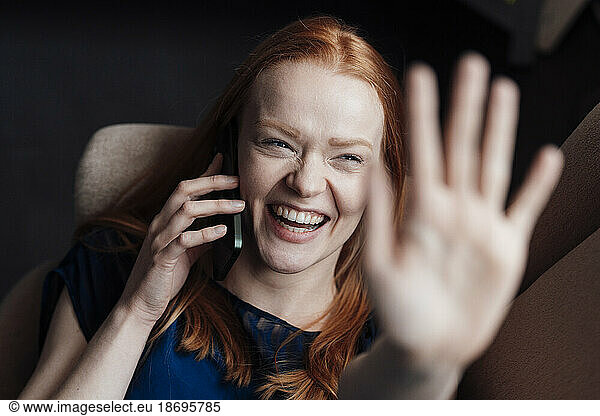 Happy woman showing palm and talking on smart phone