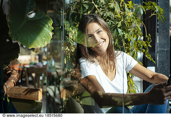 Happy woman sitting by cafe's glass window