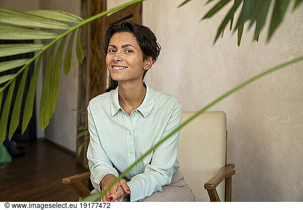 Happy woman sitting in front of wall at home