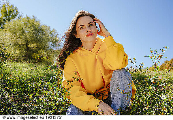 Happy woman sitting in nature on sunny day