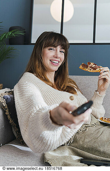 Happy woman spending leisure time watching TV at home