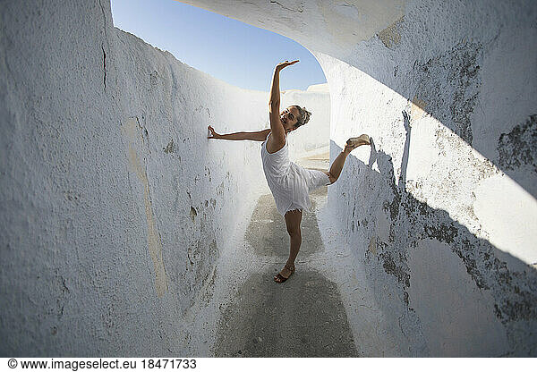 Happy woman standing amidst whitewashed wall