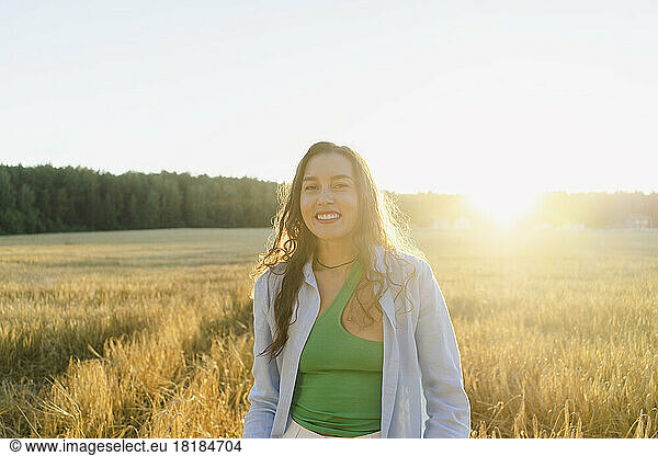 Happy woman standing at field at sunset