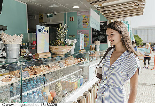 Happy woman standing by display at bakery