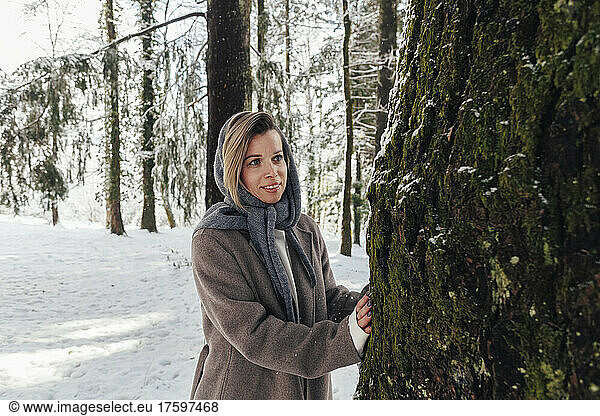 Happy woman standing by tree at forest