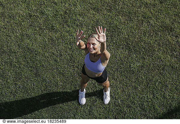 Happy woman standing on grass gesturing in park
