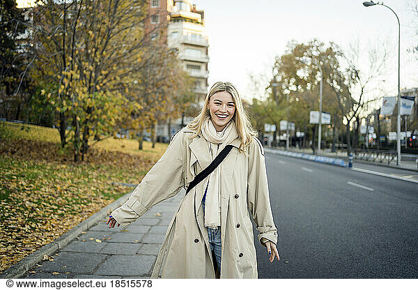 Happy woman strolling on sidewalk in city