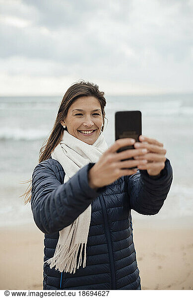 Happy woman taking selfie on beach