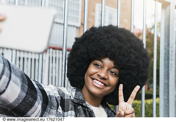 Happy woman taking selfie showing peace sign