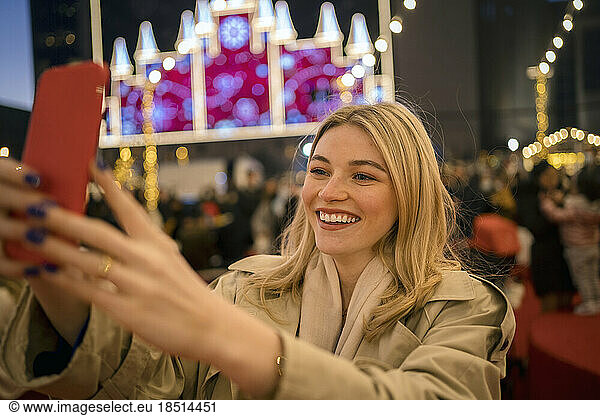 Happy woman taking selfie through smart phone at festival