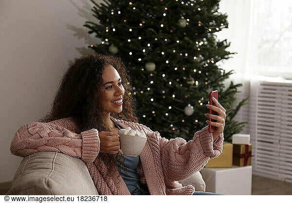 Happy woman taking selfie with cup of marshmallow cocoa