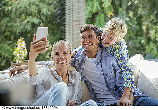 Happy woman taking selfie with family at home