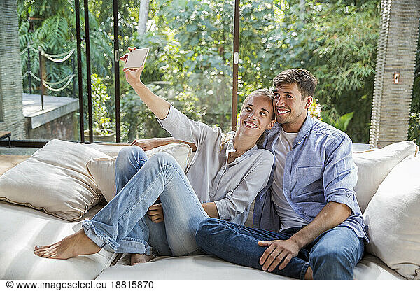Happy woman taking selfie with man at home