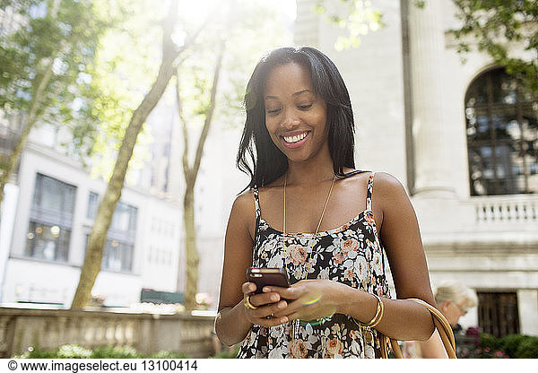Happy woman text messaging while standing in city