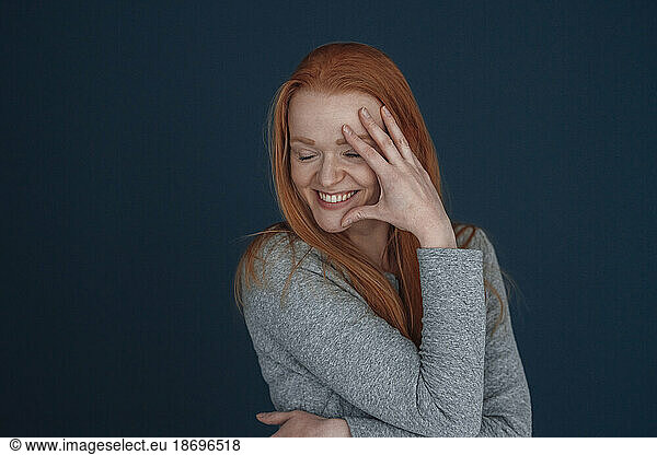 Happy woman touching face against blue background