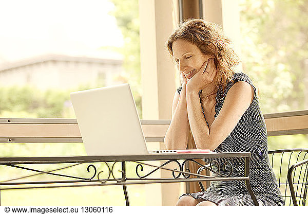 Happy woman using laptop computer while sitting at home
