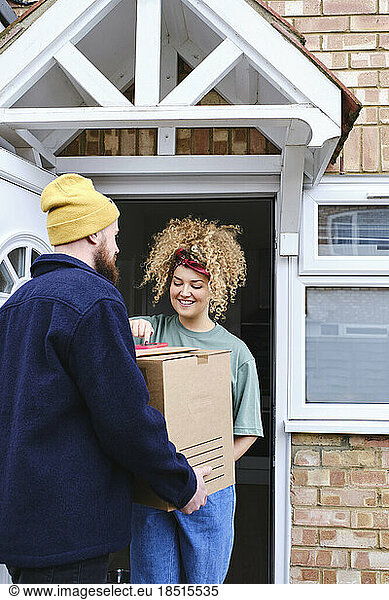 Happy woman using smart phone and taking delivery of packages