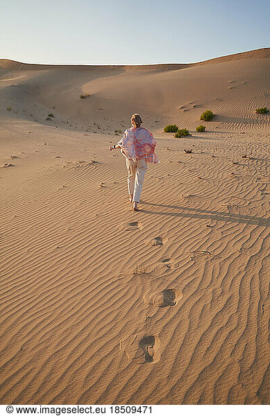 Happy woman walks in the desert during a safari. Vertical shot.