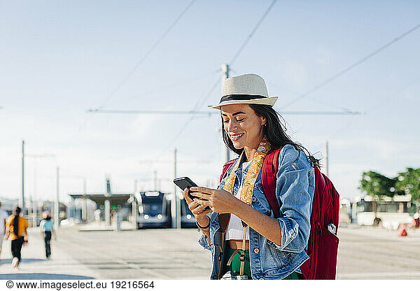 Happy woman wearing hat using mobile phone