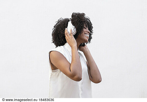 Happy woman wearing headphones enjoys listening to music over white background