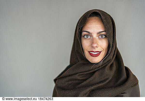 Happy woman wearing hijab against gray background