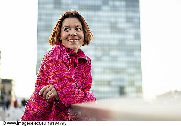 Happy woman wearing sweater leaning on railing
