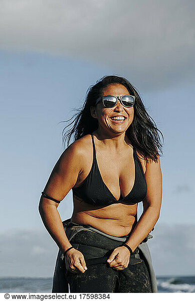 Happy woman wearing wetsuit and bikini at beach