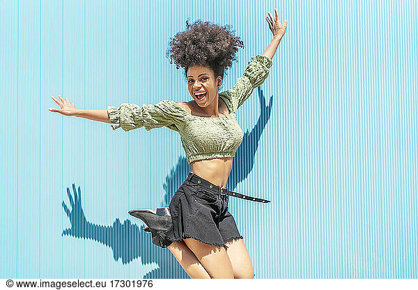happy woman with afro hair jumping for joy