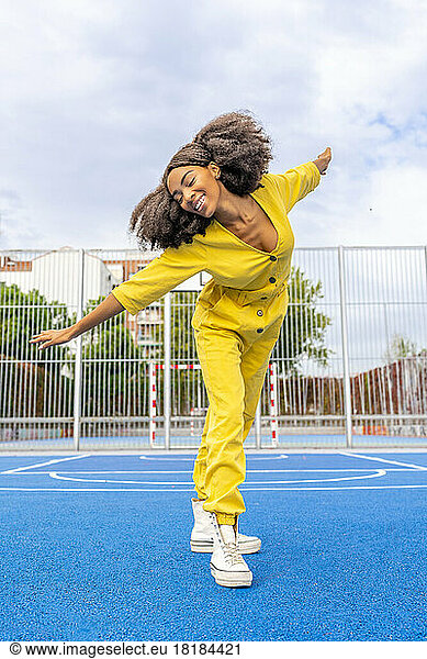 Happy woman with Afro hairstyle dancing on basketball court