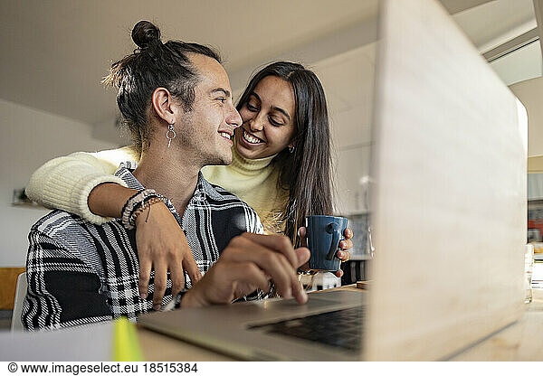 Happy woman with arm around boyfriend at home office