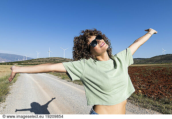 Happy woman with arms outstretched standing on road