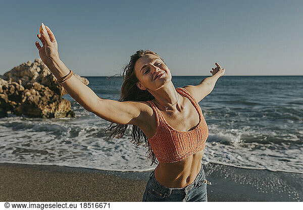Happy woman with arms raised enjoying at beach