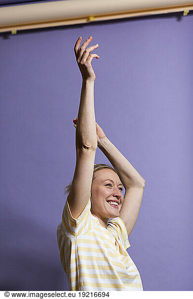 Happy woman with arms raised enjoying in studio