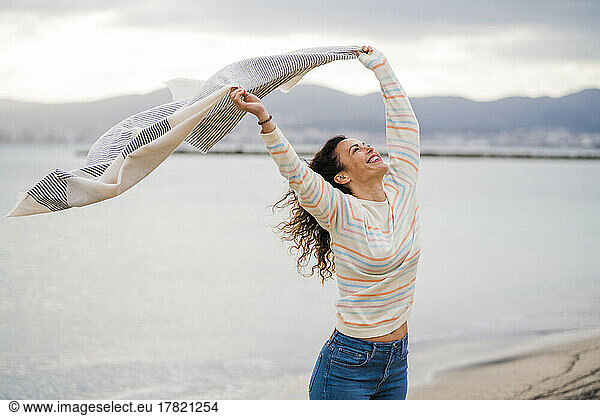 Happy woman with arms raised holding scarf
