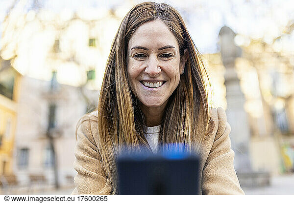 Happy woman with brown hair text messaging through smart phone