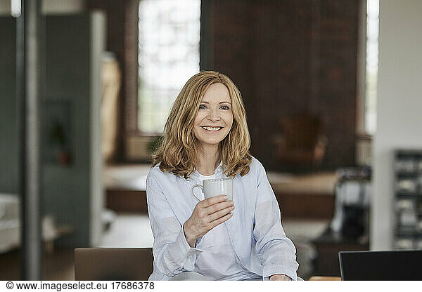 Happy woman with coffee cup sitting at home