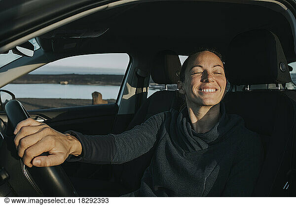 Happy woman with eyes closed sitting in car