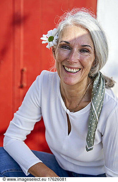 Happy woman with gray hair wearing flower on sunny day